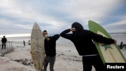 FILE - Surfers bump elbows as they protest against the nationwide lockdown regulations that allow exercise but not water activities, amid the coronavirus disease (COVID-19) outbreak, at Muizenberg beach in Cape Town, South Africa, May 5, 2020.