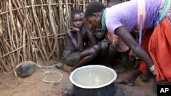 In this photo taken Tuesday, Oct. 17, 2017, a Karamojong woman prepares a meal at her village in the semi-arid savannah region of Karamoja, in northeastern Uganda. (AP/Adelle Kalakouti)