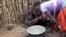 In this photo taken Tuesday, Oct. 17, 2017, a Karamojong woman prepares a meal at her village in the semi-arid savannah region of Karamoja, in northeastern Uganda. (AP/Adelle Kalakouti)