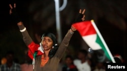 FILE - A woman flashes the victory sign during the first anniversary of the start of the uprising that toppled long-time ruler Omar al-Bashir, at the Friendship Hall in Khartoum, Sudan, Dec. 25, 2019. 