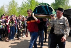 Men carry a coffin with the body of Elvira Ignatieva, a teacher who was killed in a shooting at a school on Tuesday, in Kazan, Russia, May 12, 2021.