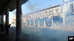 Iraqi riot police fire tear gas while blocking al-Rashid Street during clashes with anti-government demonstrators in al-Rashid Street, in Baghdad, Iraq, Nov. 17, 2019.