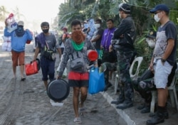 Residents carry their belongings as authorities enforced total evacuation of residents living near the active Taal volcano in Agoncillo town, Batangas province, southern Philippines on Jan. 16, 2020.