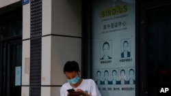 A resident wearing a mask to curb the spread of the coronavirus stand near a shuttered store that offered visa application services outside the United States Consulate in Chengdu in southwestern China's Sichuan province, July 25, 2020. 