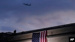A plane takes off from Washington Reagan National Airport as a large American flag is unfurled at the Pentagon ahead of ceremonies at the National 9/11 Pentagon Memorial to honor the 184 people killed in the 2001 terrorist attack on the Pentagon.