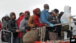 FILE - Migrants wait to disembark from a tug boat after being rescued in Porto Empedocle, Sicily, southern Italy, Feb. 17, 2015.