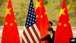 FILE - Staffers adjust Chinese and U.S. flags ahead of negotiations between Chinese and U.S. officials at the Diaoyutai State Guesthouse in Beijing, China, Feb. 14, 2019.