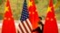 FILE - Chinese staffers adjust U.S. and Chinese flags before a session of negotiations between U.S. and Chinese trade representatives, at the Diaoyutai State Guesthouse, in Beijing, China, Feb. 14, 2019.