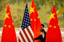 FILE - Chinese staffers adjust U.S. and Chinese flags before a session of negotiations between U.S. and Chinese trade representatives, at the Diaoyutai State Guesthouse, in Beijing, China, Feb. 14, 2019.