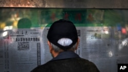 A man reads a newspaper reporting on the U.S. presidential election, at a stand in Beijing, China, Nov. 5, 2020.