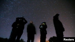 Sejumlah orang tampak menggunakan kacamata malam hari ketika mengamati objek di sekitar mereka dalam tur UFO di wilayah gurun di Sedona, Arizona, pada 14 Februari 2013. (Foto: Reuters/Mike Blake)