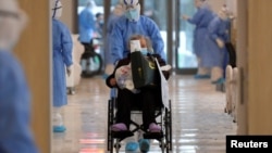 Seorang petugas mengenakan pakaian pelindung dan seorang pasien yang terinfeksi virus korona di sebuah rumah sakit di Wuhan, Provinsi Hubei, China, 10 Februari 2020. (Foto: China Daily via Reuters)
