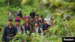 Montagnard hill tribesmen walk towards the main road after emerging from dense forest 70 km (43 miles) northeast of Ban Lung, located in Cambodia's northeastern province of Ratanakiri July 22, 2004. 