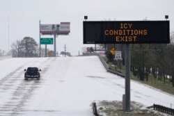 A truck drives past a highway sign on Feb. 15, 2021, in Houston. A frigid blast of weather across the U.S. plunged Texas into an unusually icy emergency Monday that knocked out power to more than 2 million people.