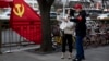 A deputized citizen gives direction to a resident near a Chinese Community Party flag on the streets of Beijing, China, Oct. 16, 2017.