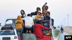 FILE - Syrian Kurds ride in the back of a vehicle to flee areas on the outskirts of the northern city of Aleppo that were formerly controlled by the Kurdish-led Syrian Democratic Forces (SDF), after they were seized by Islamist-led rebels on Dec. 2, 2024. 