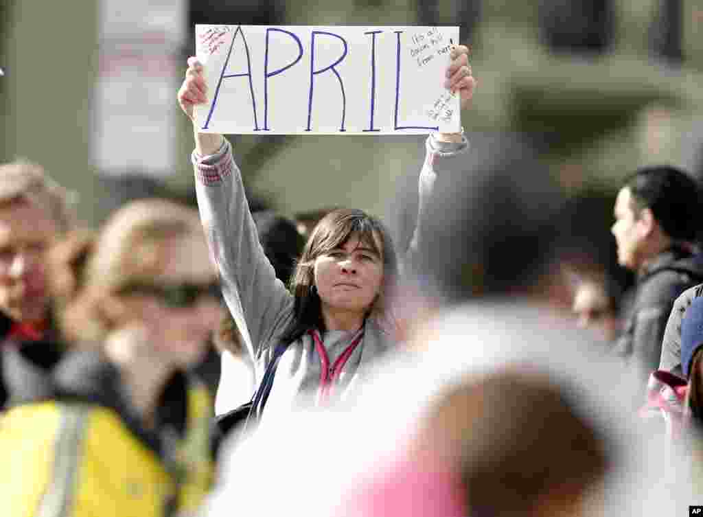 Justine Franco dari Montpelier, Vermont, mengangkat papan kertas saat mencari temannya yang hilang, April, yang ikut berpartisipasi untuk pertama kalinya dalam Marathon Boston 2013. (AP/Winslow Townson)