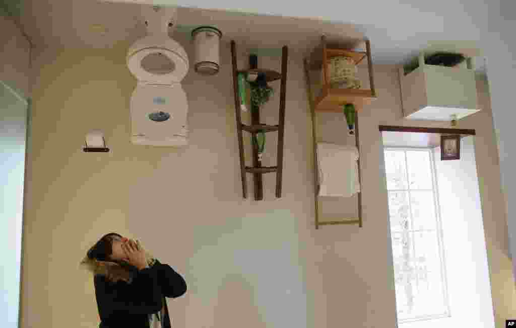 A visitor poses inside an upside-down house created by a group of Taiwanese architects at the Huashan Creative Park in Taipei.