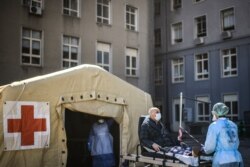 A health worker pushes a man on a stretcher towards a triage tent for suspected COVID-19 patients, outside the Santa Maria Hospital in Lisbon, Portugal, April 2, 2020.