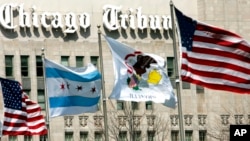 FILE - Flags wave near the Chicago Tribune Tower in Chicago, April 12, 2006. Newspaper publisher Tribune, which owns the Chicago Tribune, the Baltimore Sun and other newspapers, said Feb. 16, 2021, it has agreed to be sold to Alden Global Capital.