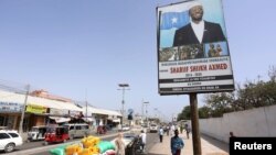 People walk along a street with the campaign billboard of Somalia's Presidential candidate Sharif Sheikh Ahmed in Somalia's capital Mogadishu, Feb. 6, 2017. 