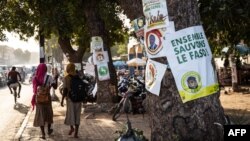 Des écolières défilent devant les affiches de la campagne présidentielle, à Ouagadougou le 6 novembre 2020, lors de la campagne présidentielle avant les élections présidentielles du 22 novembre 2020.
