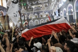 Mourners carry the body of Iraqi anti-government activist Ihab al-Wazni (Ehab al-Ouazni) during his funeral at the Imam Hussein Shrine in the central holy shrine city of Karbala on May 9, 2021.