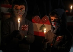 Children take part in a vigil for the victims of the deadly explosion which devastated the port and large parts of the city of Beirut, in front of the Lebanon Embassy in Santiago, Chile, Aug. 10, 2020.