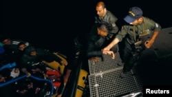 FILE - A group of migrants arrive on a rubber boat after being rescued by the Tunisian coast guard off the coast of Bizerte, Tunisia, Oct. 12, 2017.