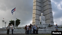 A Cuban flag flies at half-staff at Revolution Square as people gather following the announcement of the death of Cuban revolutionary leader Fidel Castro, in Havana, Cuba, Nov. 27, 2016. 