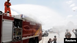 A Brazilian firefighter sprays water to cool Venezuelans outside a gym which has become a shelter for Venezuelans in Boa Vista, Brazil, Nov. 18, 2017. 