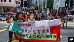 Pro-democracy demonstrators hold up a banner and portraits of jailed Chinese civil rights activists as they march in Hong Kong, June 25, 2020. US Senate bill passed targets police units that have cracked down on Hong Kong protesters.