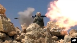 FILE - This frame grab from video released July 22, 2017, and provided by the government-controlled Syrian Central Military Media, shows a Hezbollah fighter firing a rocket-propelled grenade on the Lebanon-Syria border. 