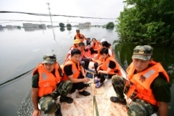 Paramilitary police officers evacuate residents from a flood-hit village with a boat in Yongxiu county of Jiujiang, Jiangxi province, China, July 14, 2020.