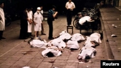 FILE: Medical workers at Beijing's Fuxingmen Hospital look at bodies of protesters killed by soldiers around Tiananmen Square on June 4, 1989.