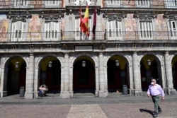 A man wearing a protective face mask walks at the usually crowded Plaza Mayor in central Madrid, Spain, March 14, 2020, after authorities ordered all shops in the region be shuttered die to the coronavirus.