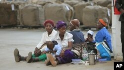 FILE - Indigenous tobacco farmers, with their children, wait to sell their tobacco, at Boka Tobacco auction floors, in Harare, Zimbabwe, May 14, 2013. 