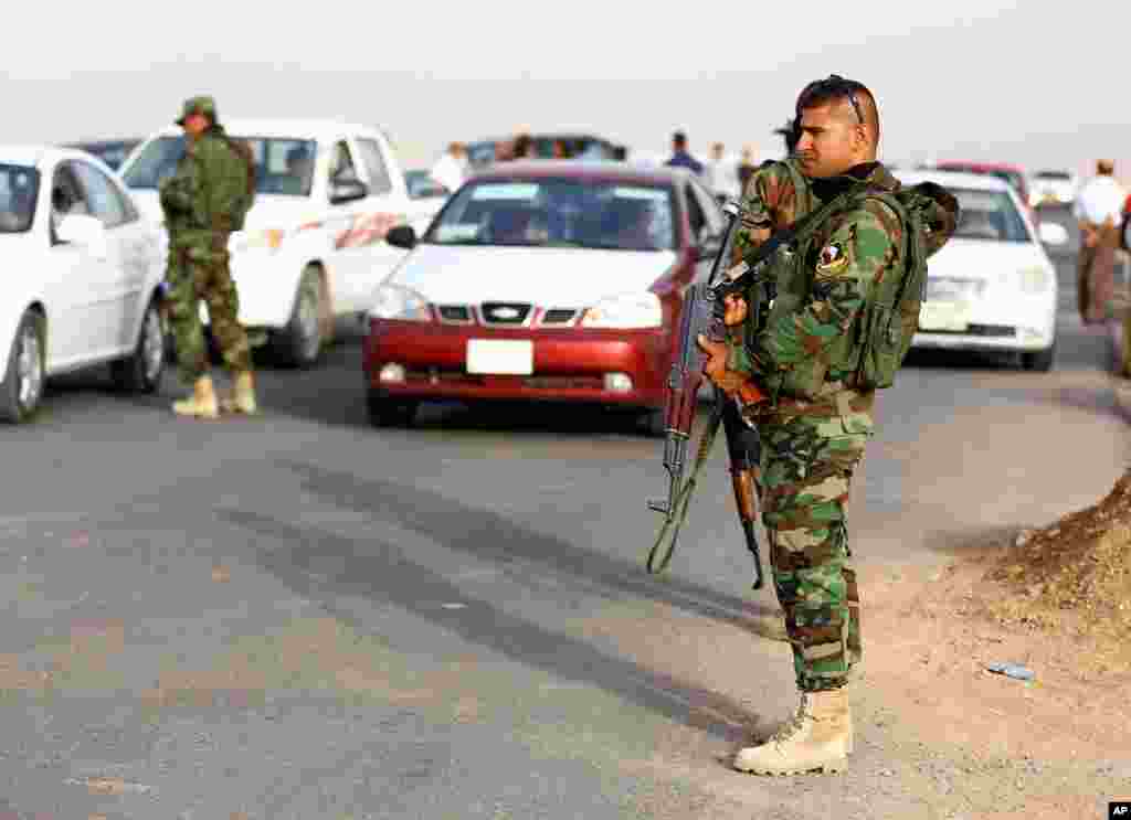 Kurdish police stand guard while refugees from Mosul head to the self-ruled northern Kurdish region outside Irbil, Iraq, June 11, 2014.