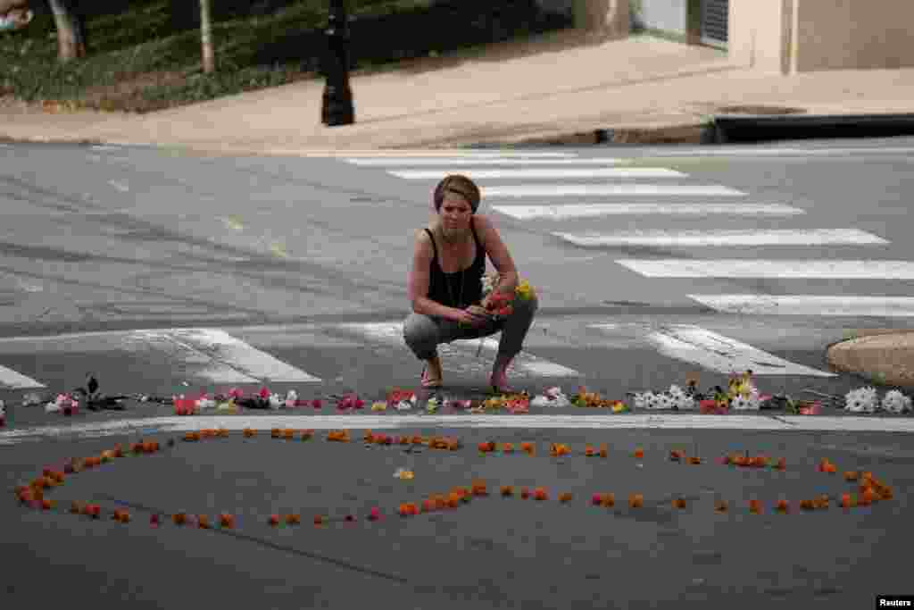 A woman kneels at a makeshift memorial for the victims of a car that plowed into counter-protesters after a "Unite the Right" rally organized by white nationalists in Charlottesville, Aug. 13, 2017.