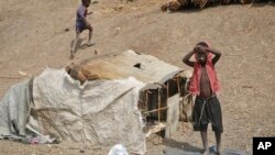 FILE - A young boy stands outside his small shelter in the United Nations protection of civilians site in Bentiu, South Sudan, Dec. 9, 2018.