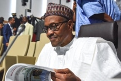 Nigerian president Muhammadu Buhari reads a document during the African Union summit at the Palais des Congres in Niamey, July 7, 2019.