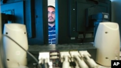 FILE - A computer forensic examiner works for the Department of Defense in Linthicum, Maryland, Aug. 11, 2011. Hackers and hostile nations are launching increasingly sophisticated cyberattacks against the U.S. 