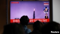 People watch a TV broadcasting file footage of a news report on North Korea firing a ballistic missile off its east coast, in Seoul, South Korea, October 19, 2021. 