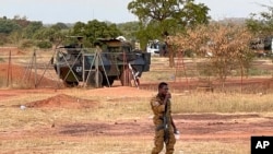 Un soldat burkinabé passe devant un véhicule blindé de transport de troupes français faisant partie d'un convoi militaire français en direction du Niger, arrêté par des manifestants à Kaya, Burkina Faso, le 20 novembre 2021.