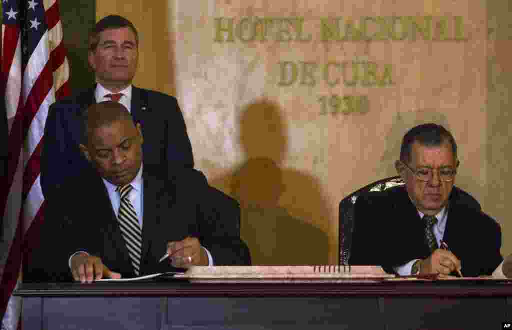 U.S.Transportation Secretary Anthony Foxx and Cuba's Minister of Transportation Adel Yzquierdo Rodriguez, right, sign the airline transportation agreement as Assistant Secretary of State for Economic and Business Affairs Charles Rivkin, top left, looks on