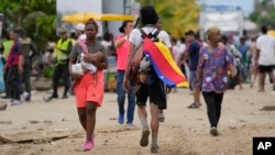 ARCHIVO - Un migrante porta una bandera venezolana en Necoclí, Colombia, un punto de parada para los migrantes que toman barcos a Acandi que conduce al Tapón del Darién, el jueves 13 de octubre de 2022.