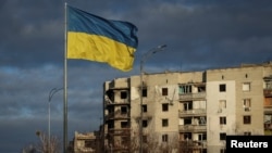 La bandera de Ucrania flota junto a edificios destrtruidos por ataques rusos en Borodianka, en la región de Kiev, el 15 de febrero de 2023.
