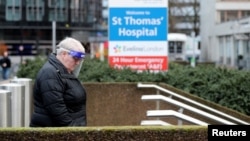 FILE - A person wearing personal protective equipment walks outside St Thomas' Hospital in London, Dec. 12, 2021.