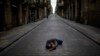 Seorang pria tidur di tengah jalan yang sepi di Barcelona, Spanyol, saat diberlakukannya karantina wilayah tersebut, 17 April 2020. (Foto: dok).