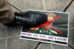 A person steps on a picture of Myanmar's army chief Min Aung Hlaing with his face crossed out after the military seized power in a coup in Myanmar, outside United Nations venue in Bangkok, Thailand, Feb. 2, 2021.